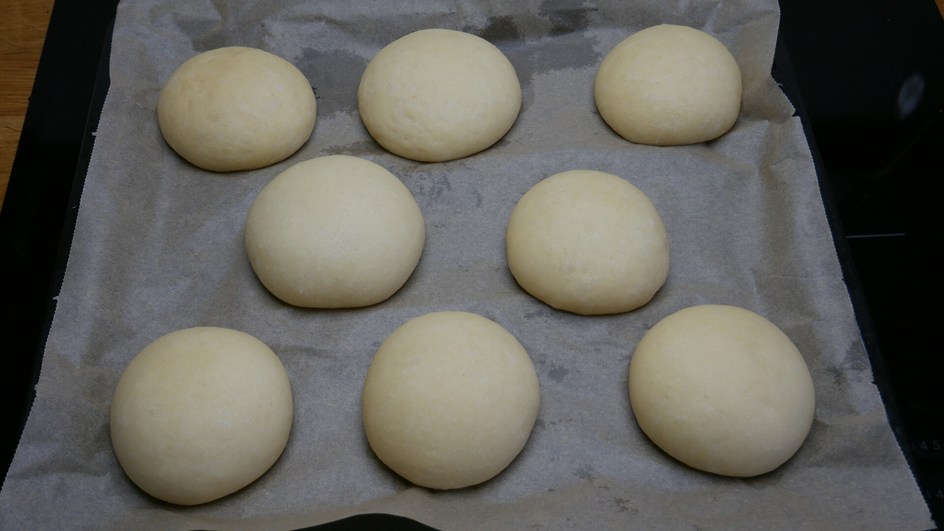 balls of yeast dough on a baking tray after proving